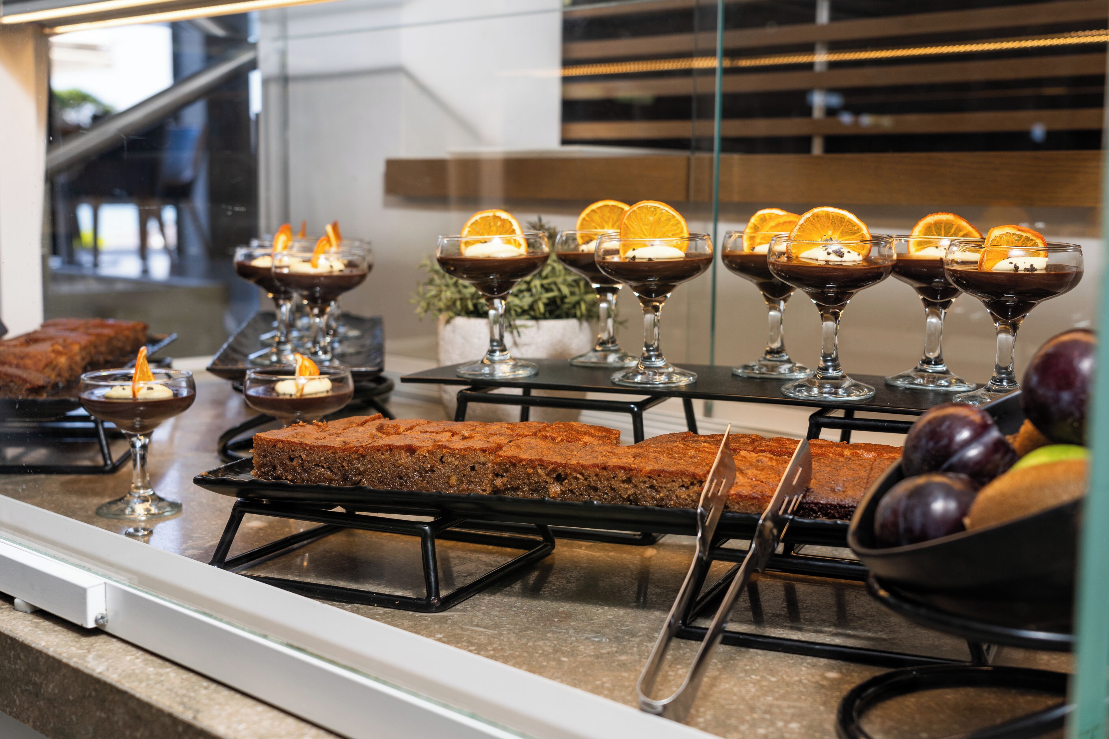 A dessert display with chocolate desserts and glasses of chocolate dessert with orange slices.