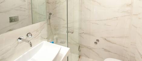 Une salle de bain moderne avec un lavabo en marbre, une douche en verre et des toilettes.