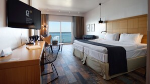 Habitación de hotel con cama, escritorio, silla y televisor montado en la pared.