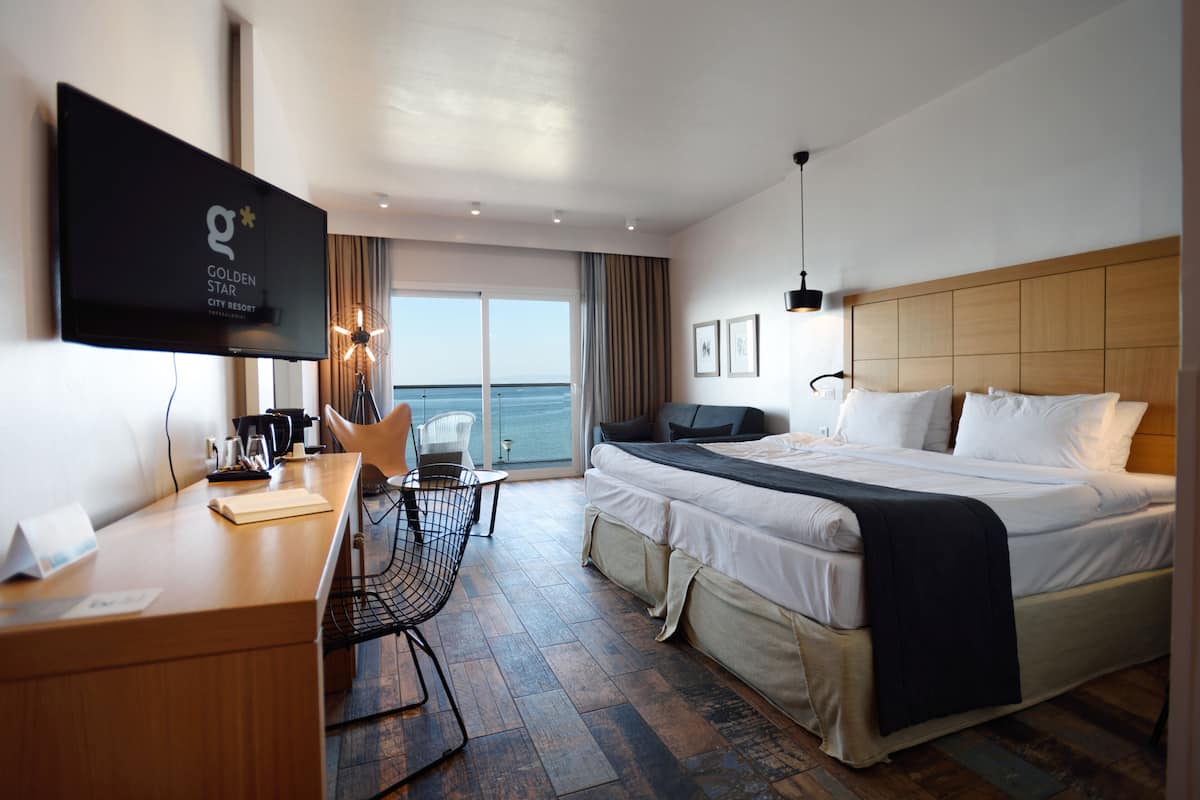 Habitación de hotel con cama, escritorio, silla y televisor montado en la pared.