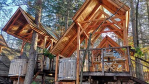 Estructura de casa en árbol de madera con varios niveles y plataformas, rodeada de árboles.