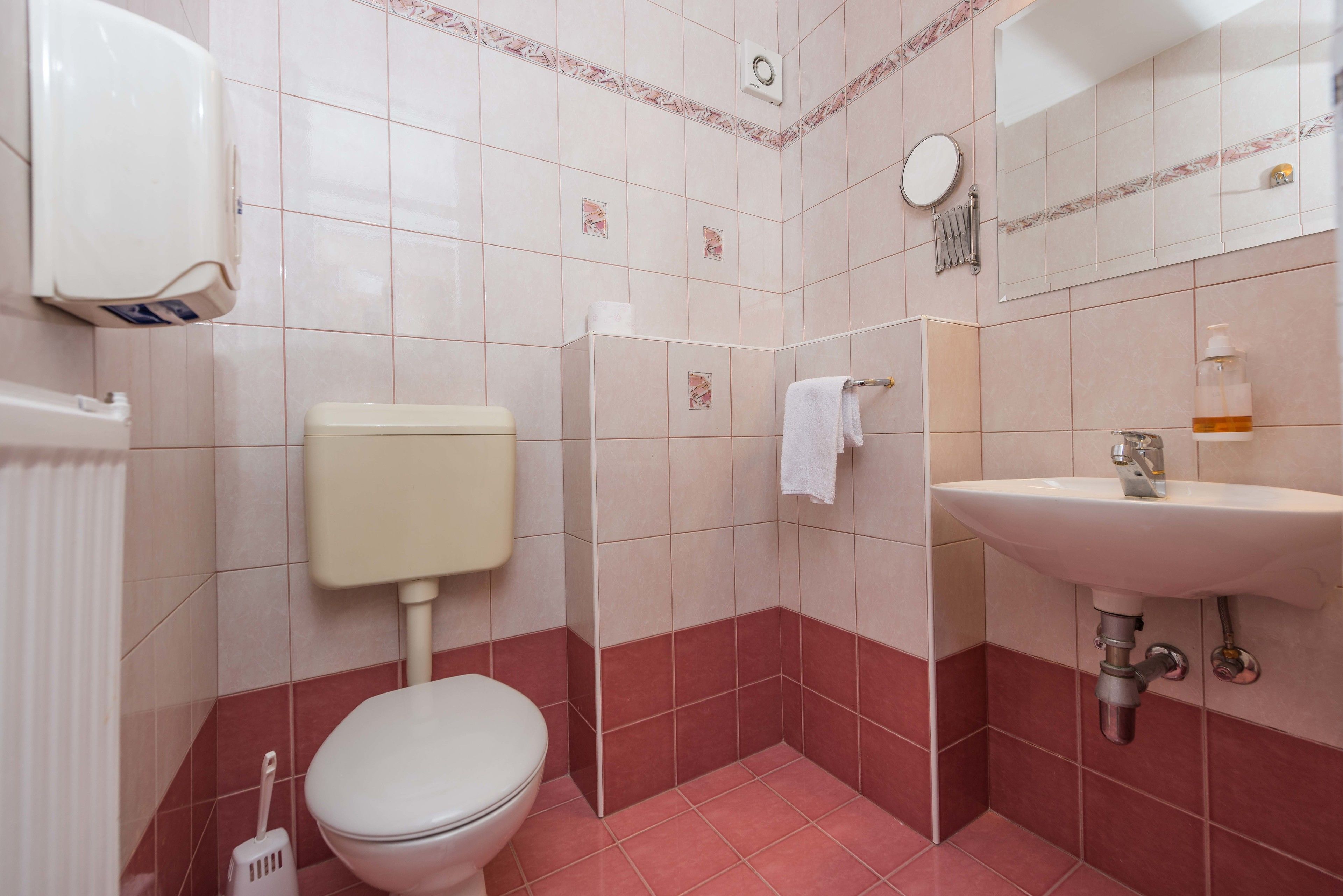 A bathroom with a toilet, sink, and hand dryer.