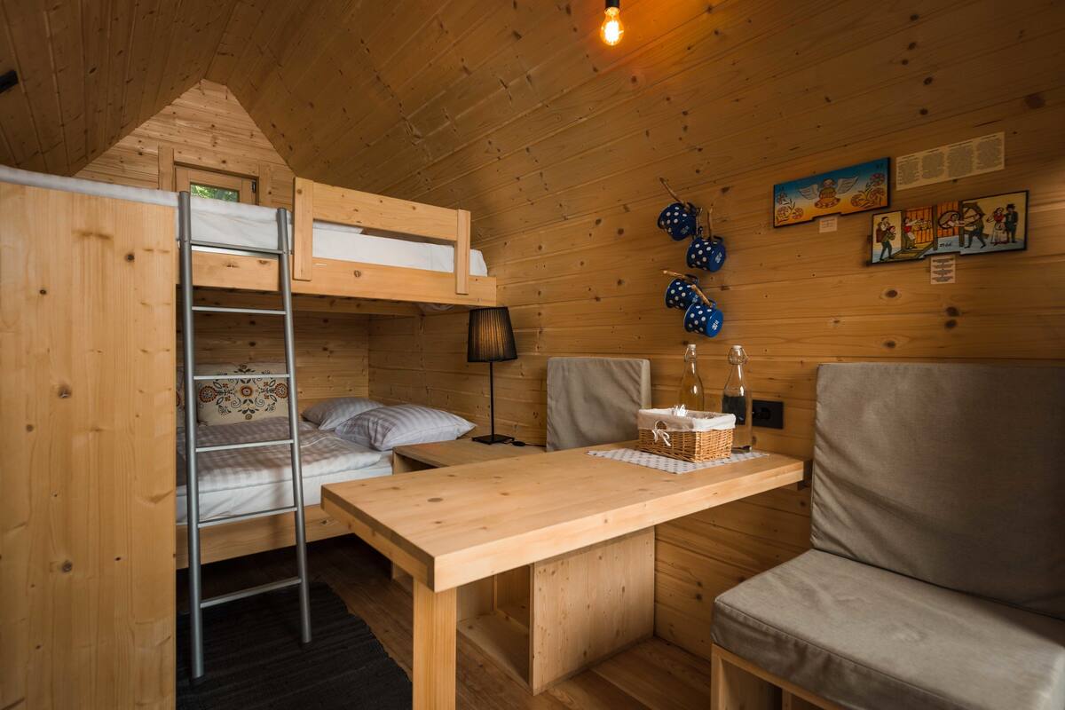 A wooden cabin with bunk beds, a table, and a couch.