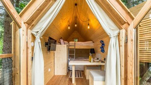 Una cabaña de madera acogedora con una cama litera, un escritorio con lámpara y una pequeña mesa.
