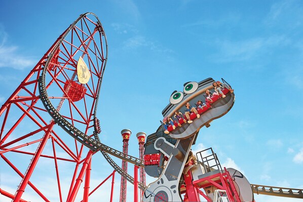 A roller coaster with a dinosaur theme, including a large dinosaur head and a red track. - Ancora Salou Apartamentos (Salou)