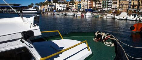 Un puerto deportivo con barcos amarrados, cielo despejado y edificios al fondo.
