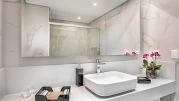 Un baño moderno con un espejo grande, un lavabo blanco y una pared de mármol.