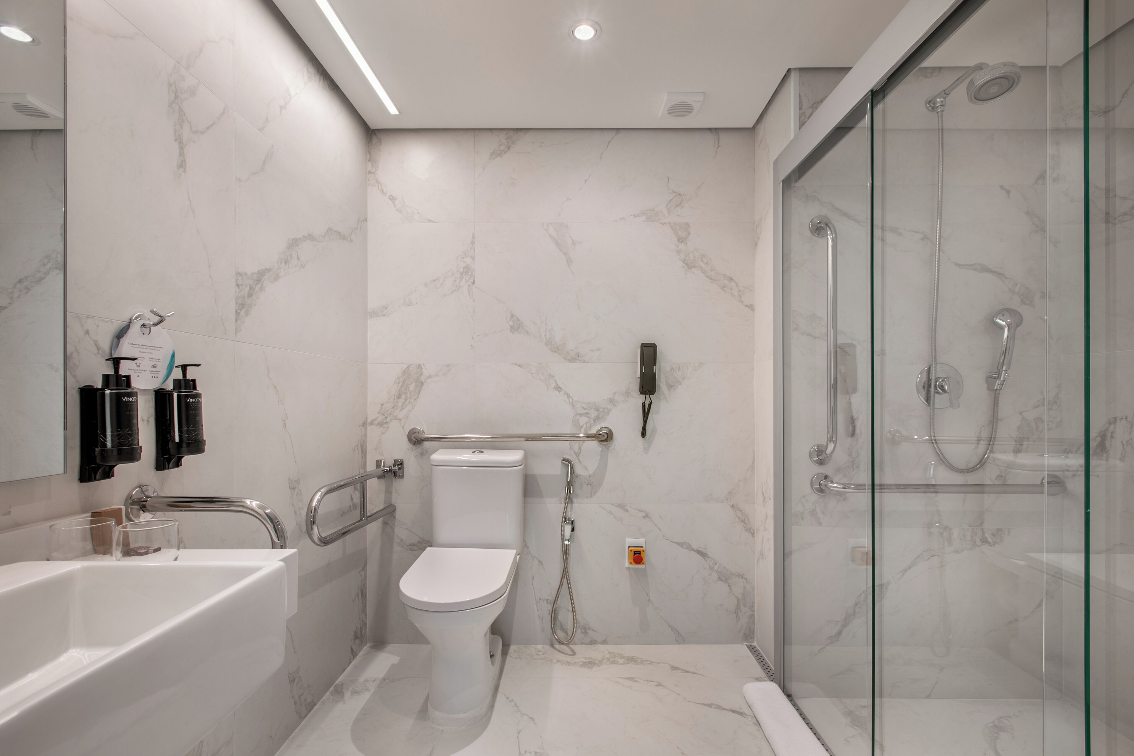 A modern bathroom with a white toilet, a glass-enclosed shower, and a white bathtub.