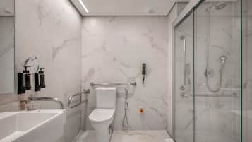 A modern bathroom with a white toilet, a glass-enclosed shower, and a white bathtub.