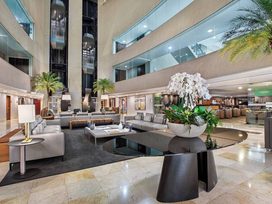 Eine großzügige Lobby mit einem zentral platzierten Couchtisch, einer Sitzecke und einer Rezeption.