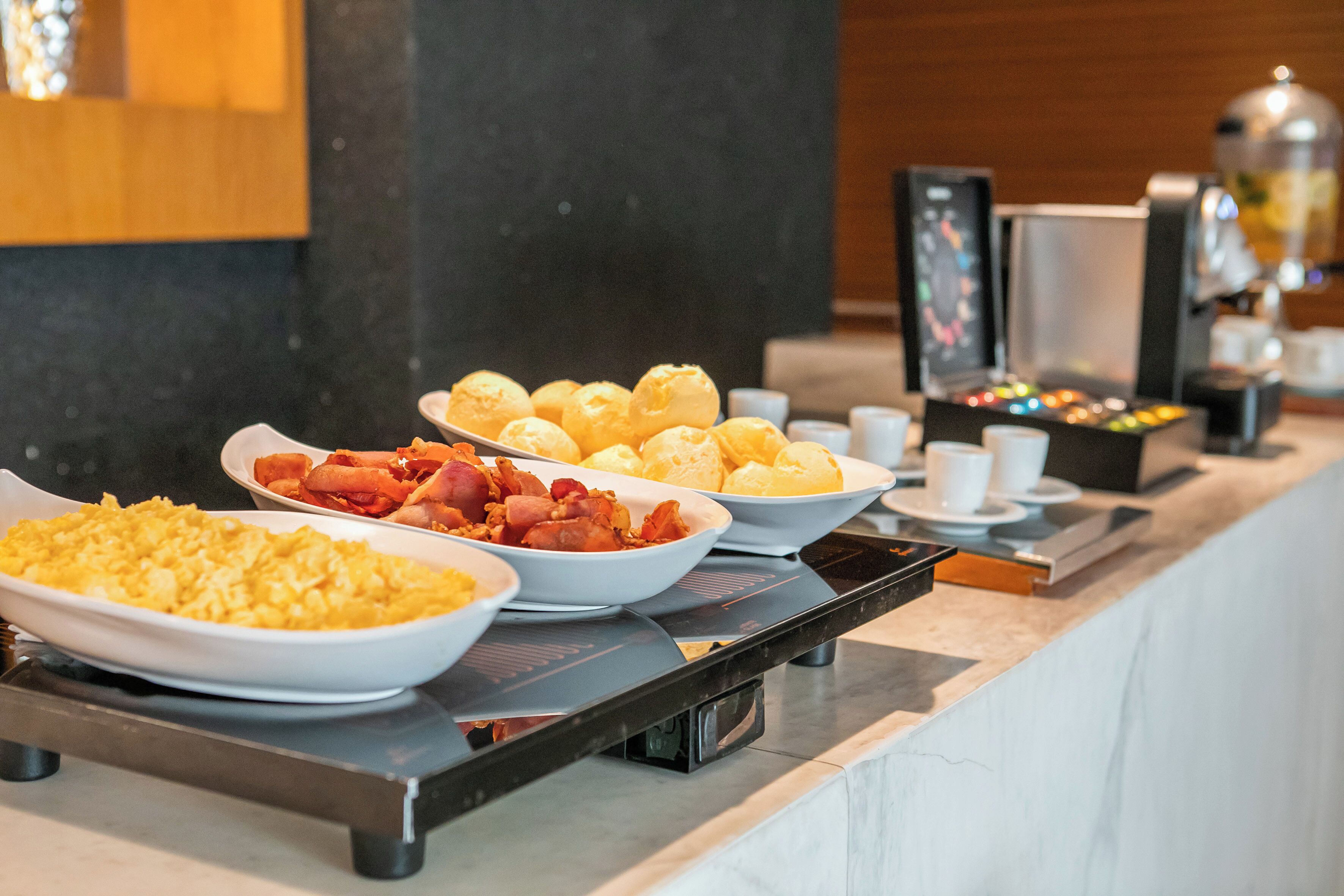 Un bufé con diversos alimentos, como huevos revueltos, tocino y pastelería.