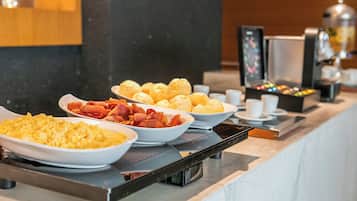 Un bufé con diversos alimentos, como huevos revueltos, tocino y pastelería.