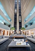 Um hall espaçoso com teto alto, mobiliário moderno e área de estar central.