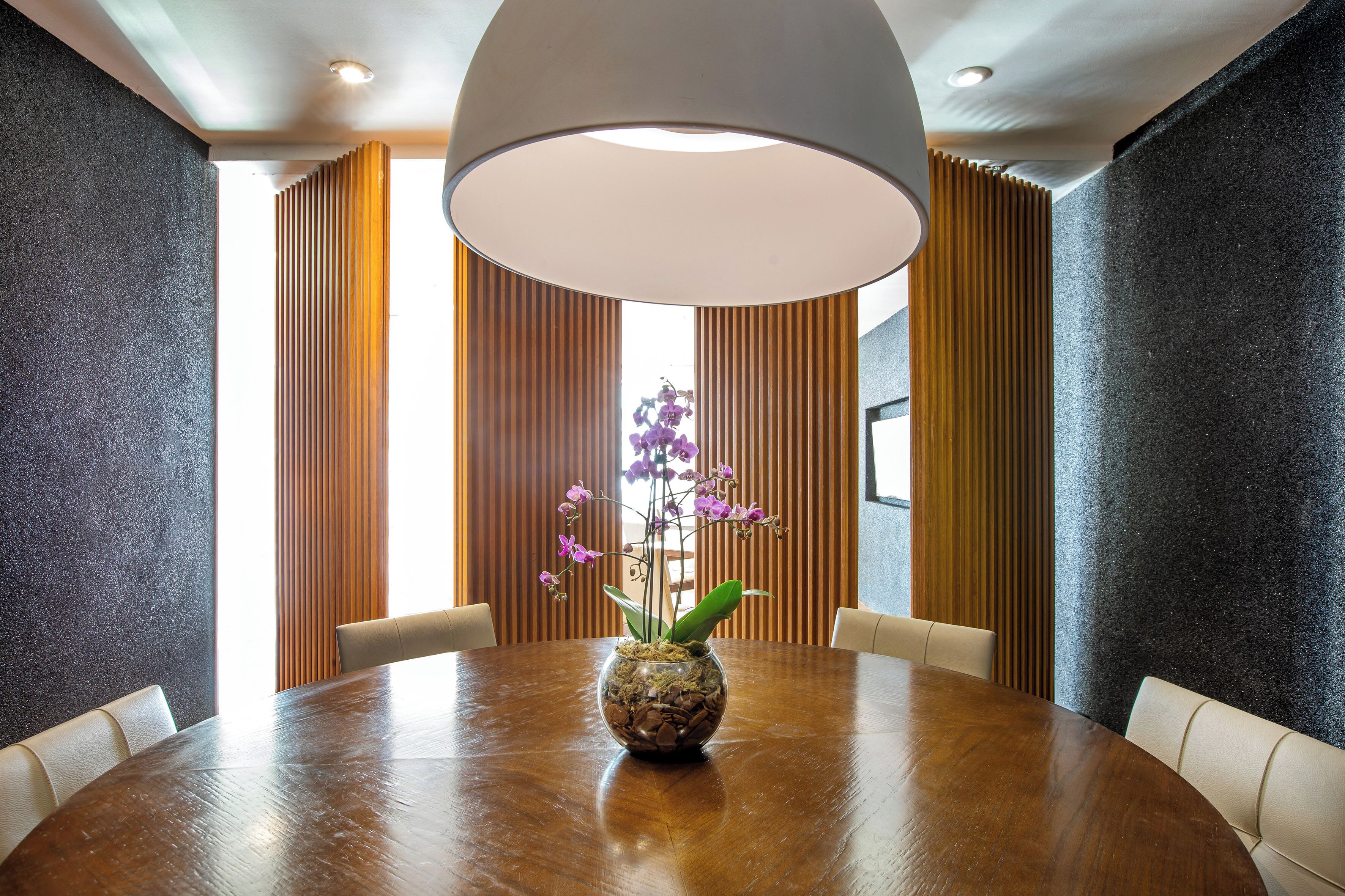 A conference room with a round table, a vase with purple flowers, and a large ceiling light.