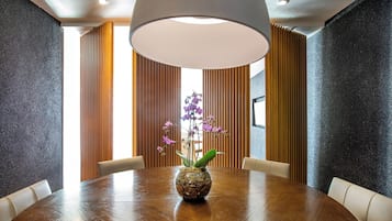 A conference room with a round table, a vase with purple flowers, and a large ceiling light.