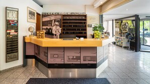 Una mesa de recepción con un reloj antiguo, cuadros enmarcados y una exhibición de automóviles clásicos.