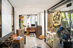 Un vestíbulo de hotel con un mostrador de recepción, sillas, un mapa y un cartel del hotel.