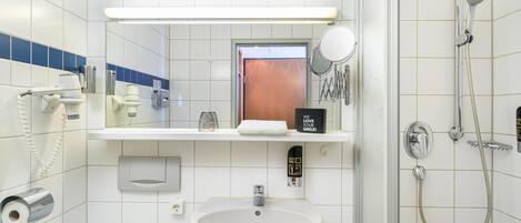A bathroom with a sink, mirror, shower, and toilet.