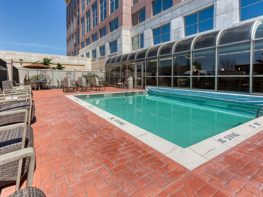 A rooftop pool area with lounge chairs and a glass-enclosed pool.