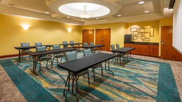 A conference room with a large table and chairs, a kitchenette, and a carpeted floor.
