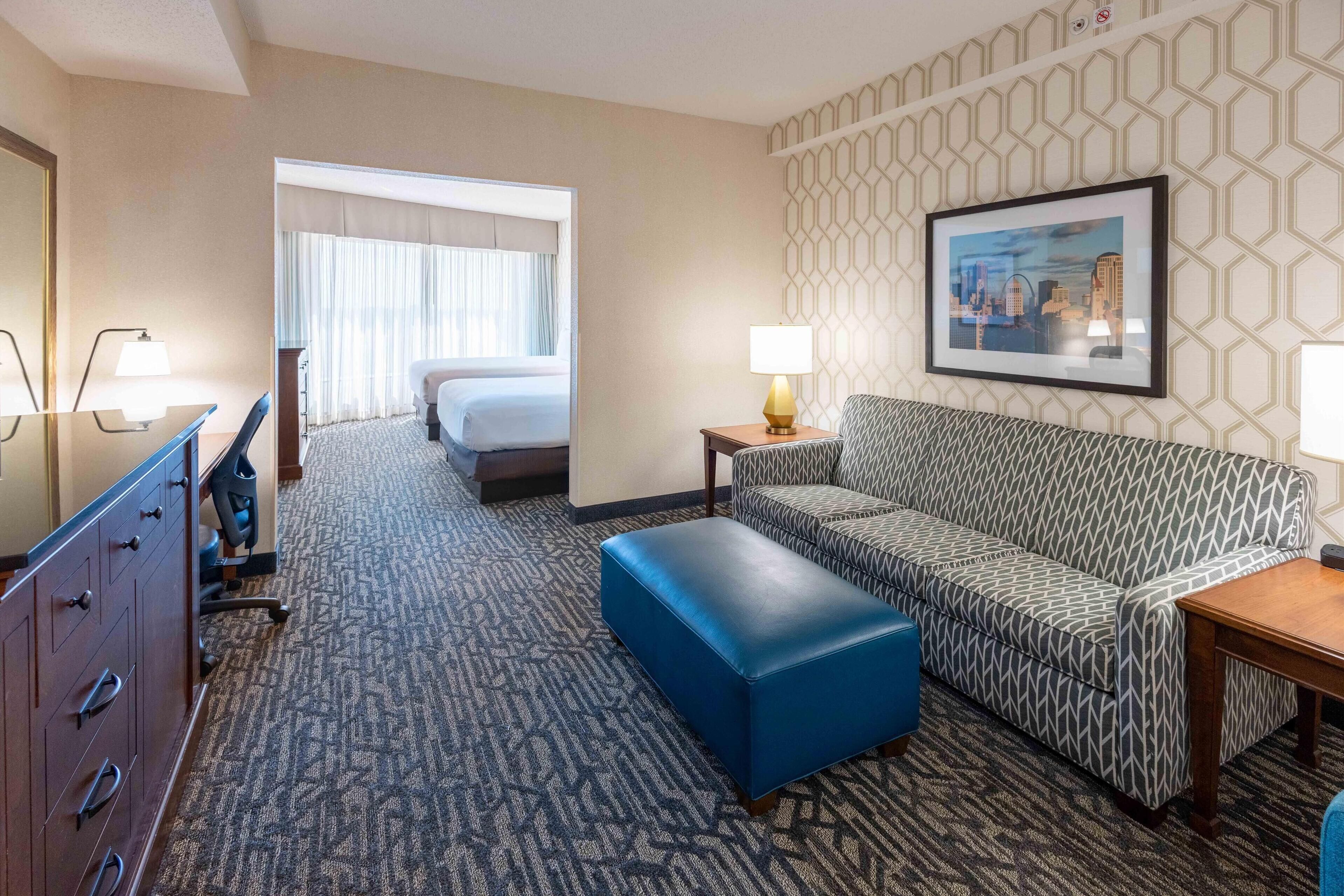 Une chambre d’hôtel avec un lit, un canapé, un bureau et une chaise.