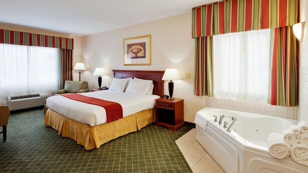 A hotel room with a large bed, a separate bathroom with a bathtub, and a chair. - Fairfield by Marriott Inn & Suites New Milford (New Milford)