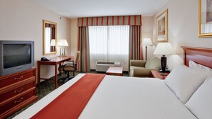 A hotel room with a large bed, a desk with a television, two chairs, a small table, and a nightstand with lamps. - Fairfield by Marriott Inn & Suites New Milford (New Milford)