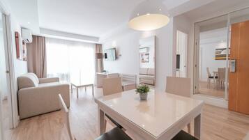 Een moderne hotelkamer met een zithoek, een bank, een televisie en een groot raam.