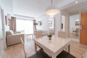 Een moderne hotelkamer met een zithoek, een bank, een televisie en een groot raam.