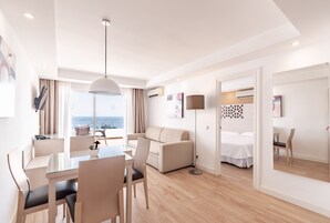 Een moderne hotelkamer met een zithoek, een bank, een bed en uitzicht op zee.