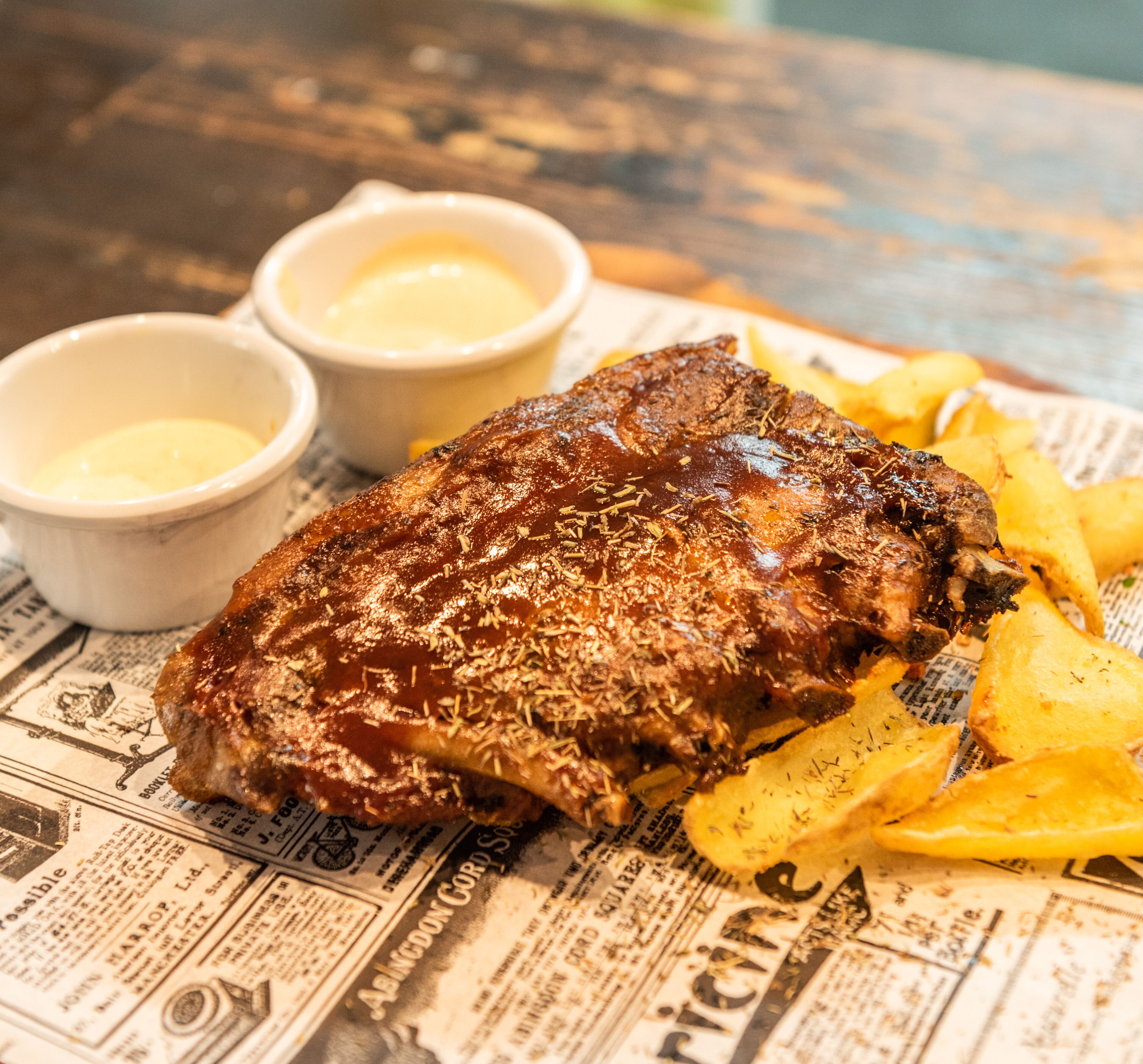 Un plato de carne acompañada de papas fritas sobre un periódico.