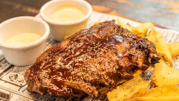 Un plato de carne acompañada de papas fritas sobre un periódico.