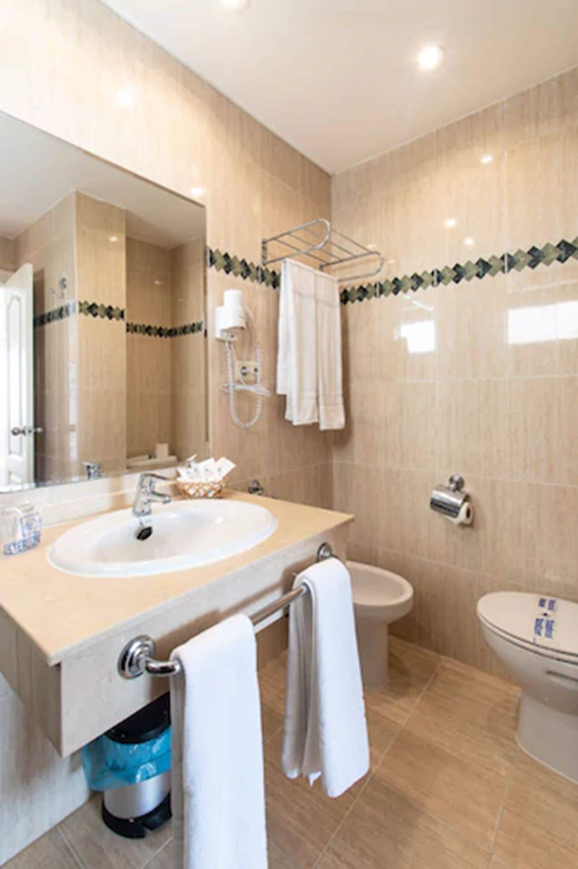 A modern bathroom with a double sink, a toilet, and a bidet.