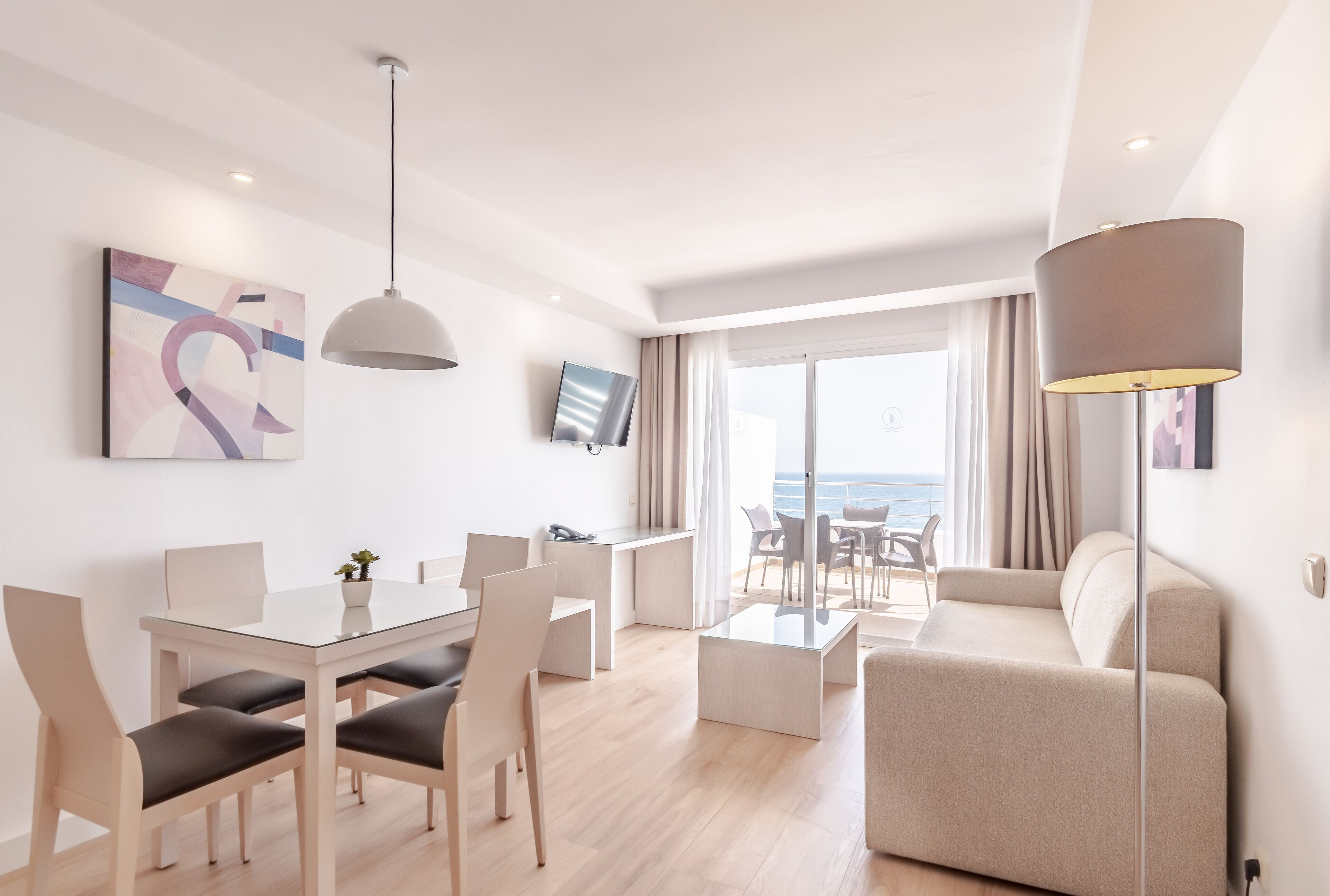 Een moderne hotelkamer met een zithoek, een bank en uitzicht op zee.
