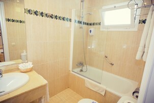 Een badkamer met een douche met glazen wand, een badkuip en een wastafel.