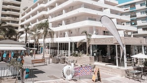 A multi-story hotel with balconies, a boardwalk area with seating, and a palm tree. - Puerto Azul Marbella (Marbella)