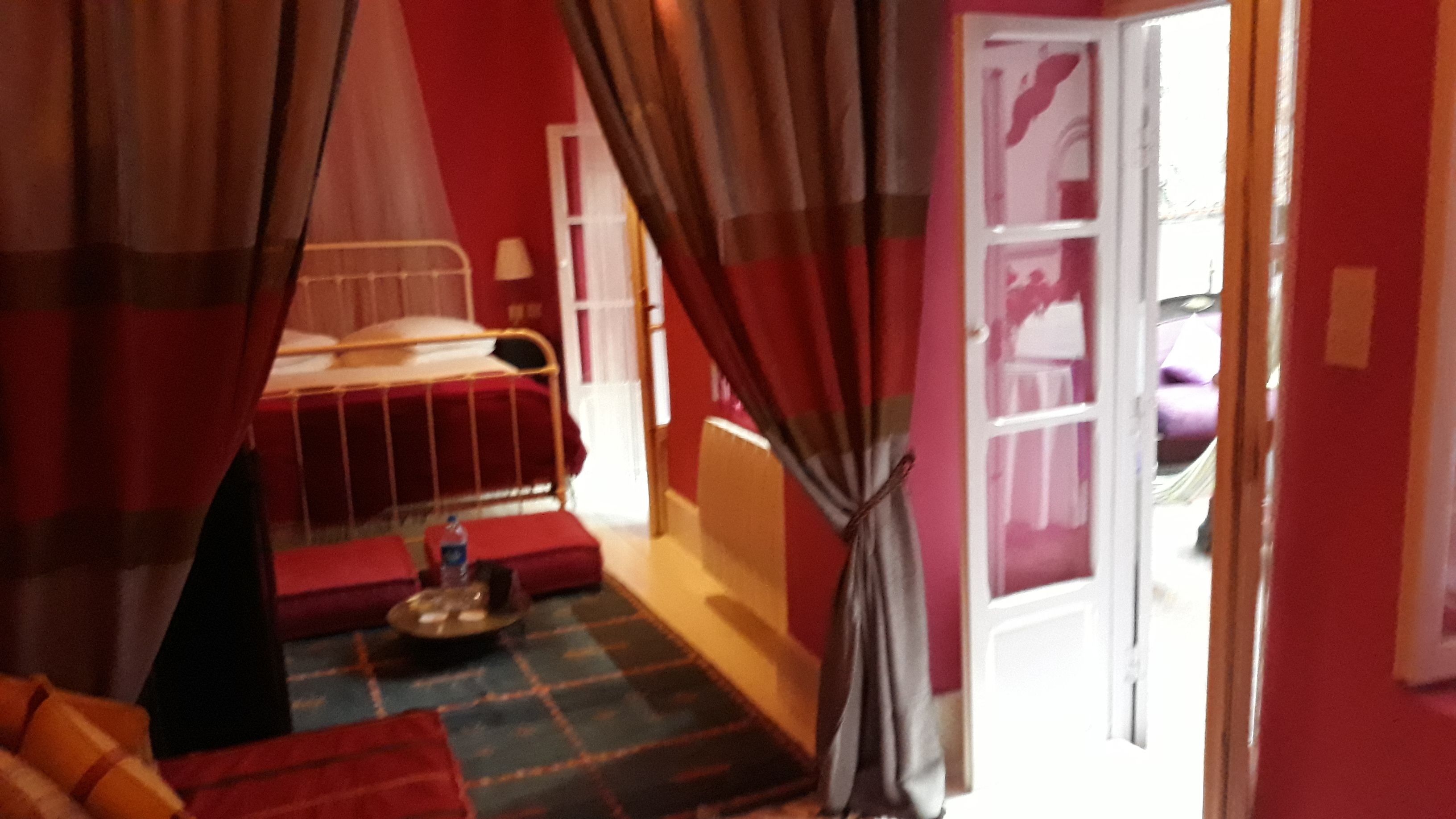 A room with a bed, a small table, and a window with curtains.