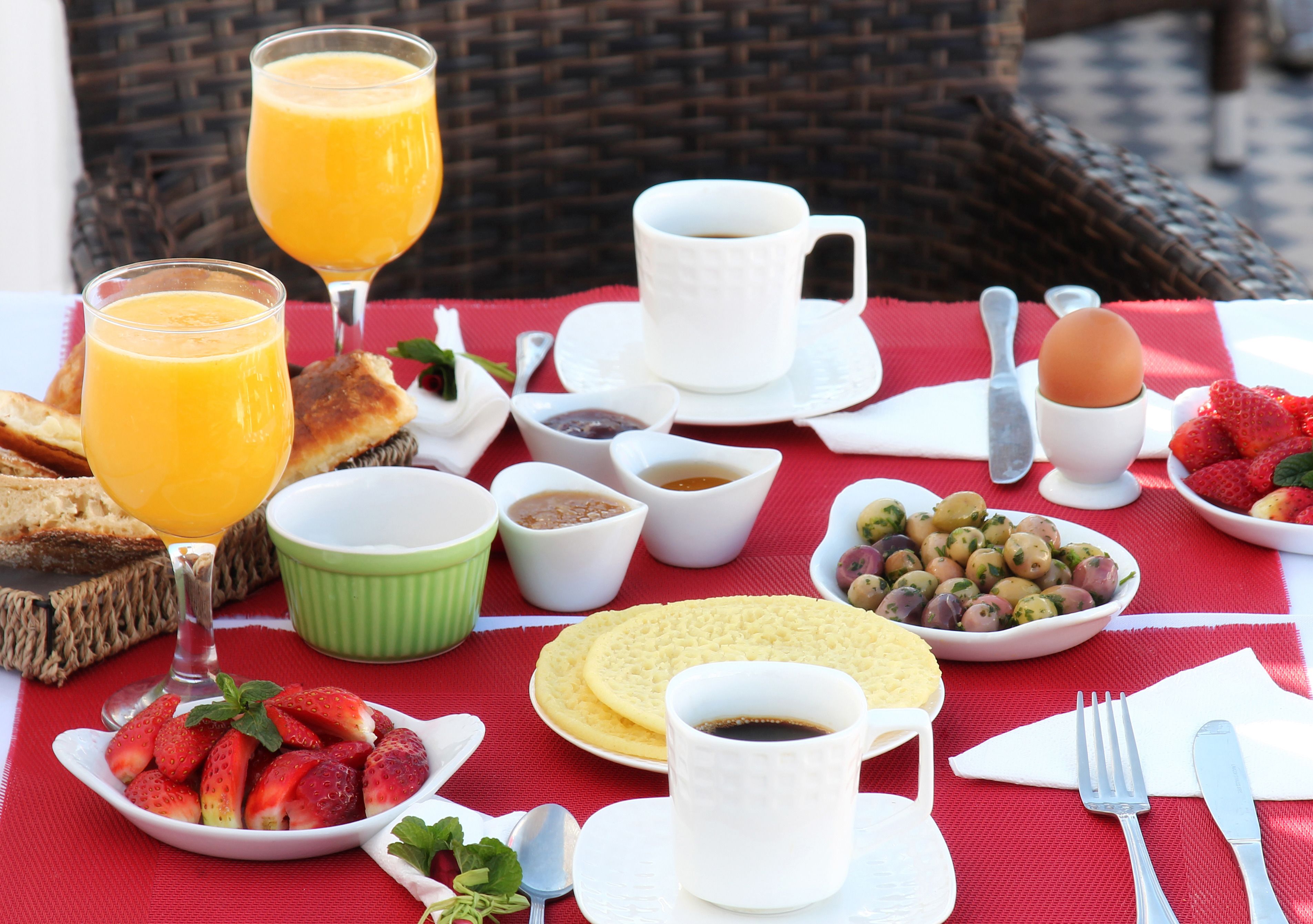 A breakfast table with various food items and drinks, including toast, strawberries, and a cup of coffee.