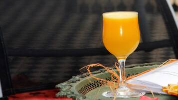 Un vaso de jugo de naranja sobre una bandeja con un plato decorativo, una libreta y un bolígrafo.