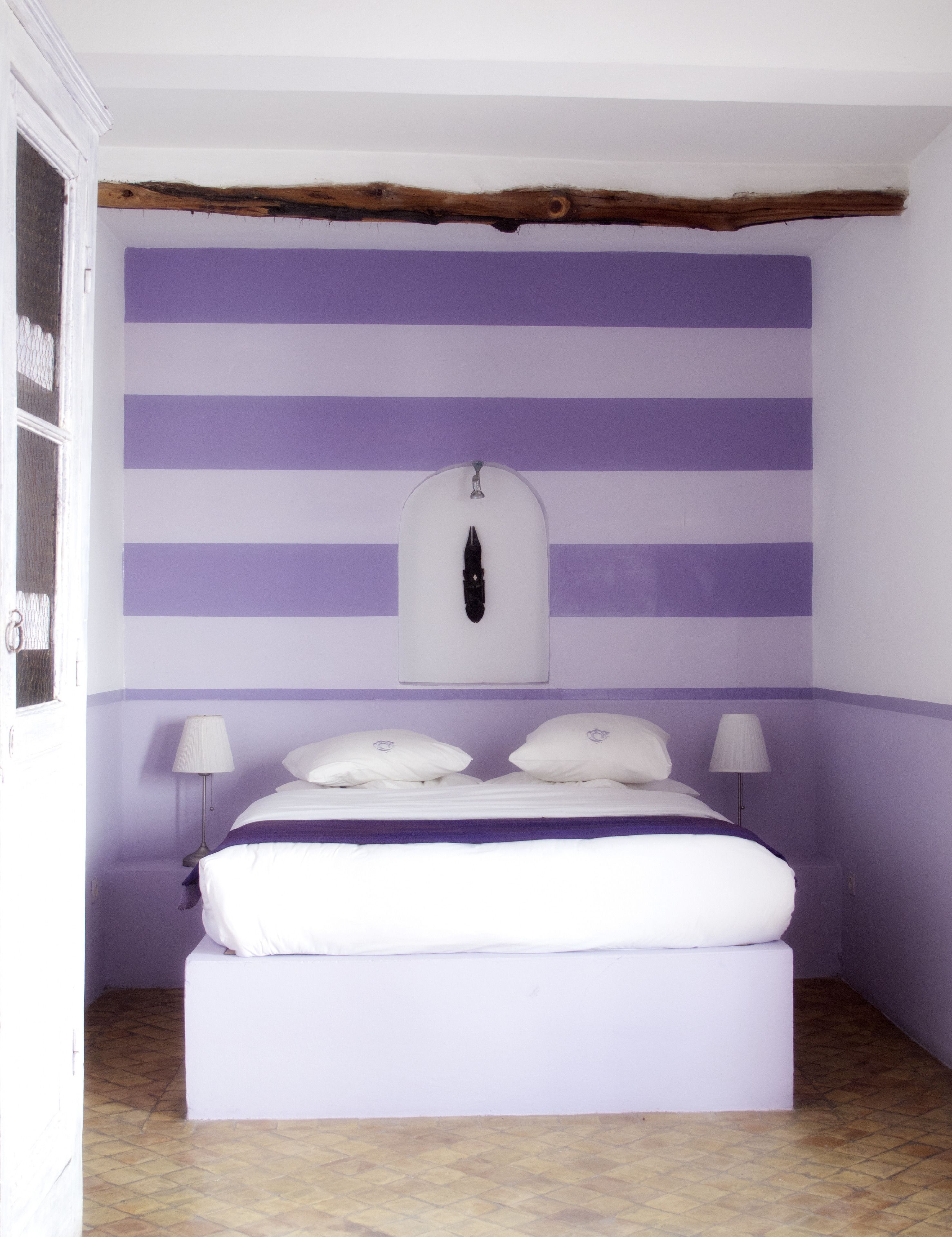 A bedroom with a bed, two bedside lamps, and a wall-mounted light fixture.
