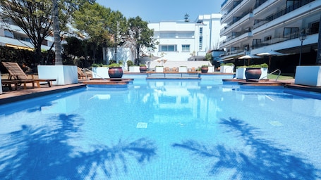 Una piscina al aire libre de temporada, sombrillas. Suites del Mar Fenals