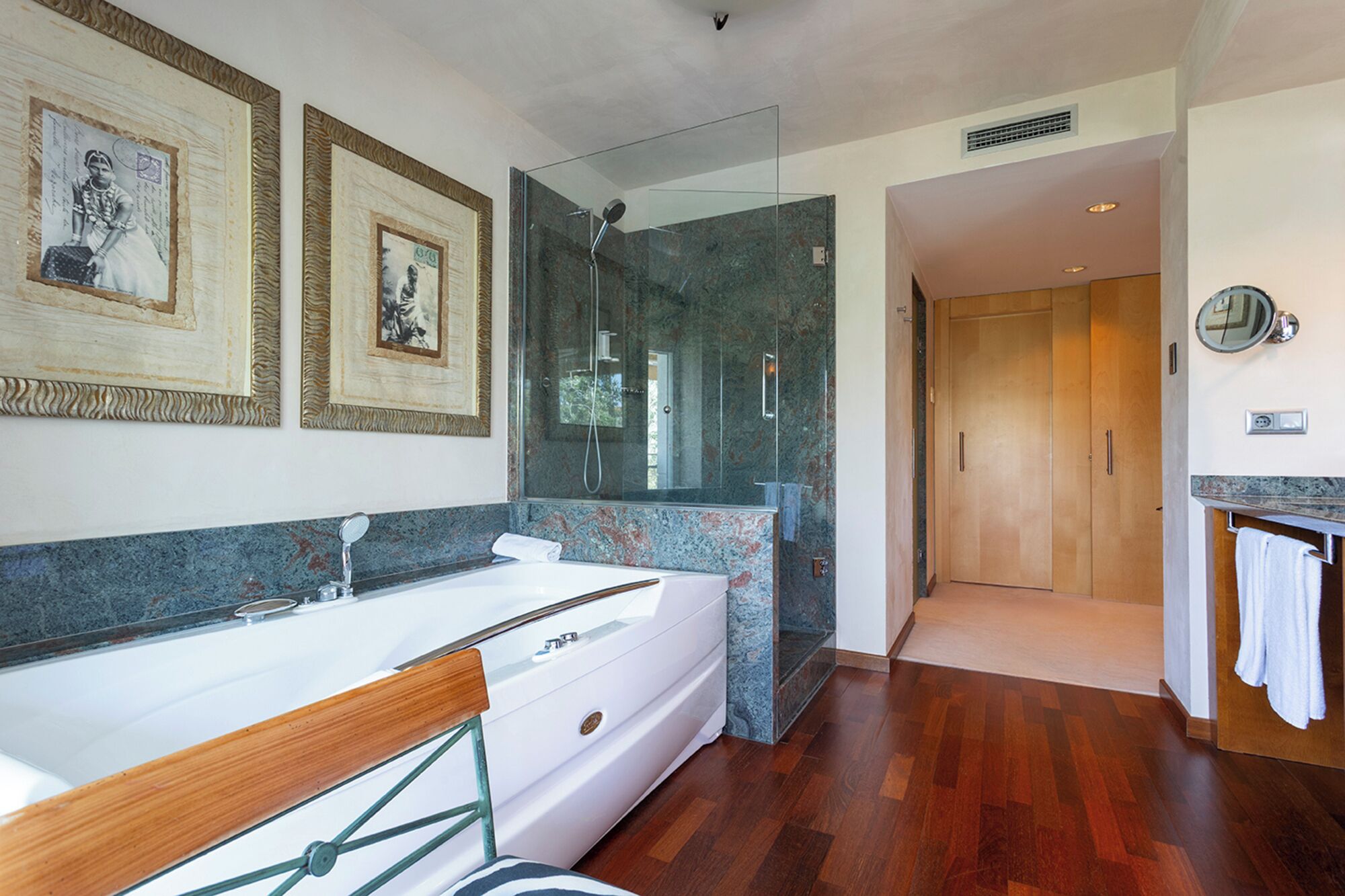 A modern bathroom with a large white bathtub, a glass-enclosed shower, and a marble countertop.