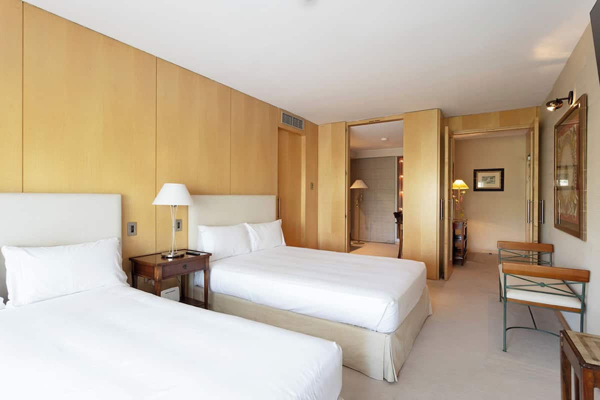 Une chambre d’hôtel avec deux lits, un bureau et une chaise.