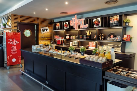 A breakfast bar with various food items, a red sign, and shelves with kitchenware and decorations.. ibis Barcelona Molins de Rei