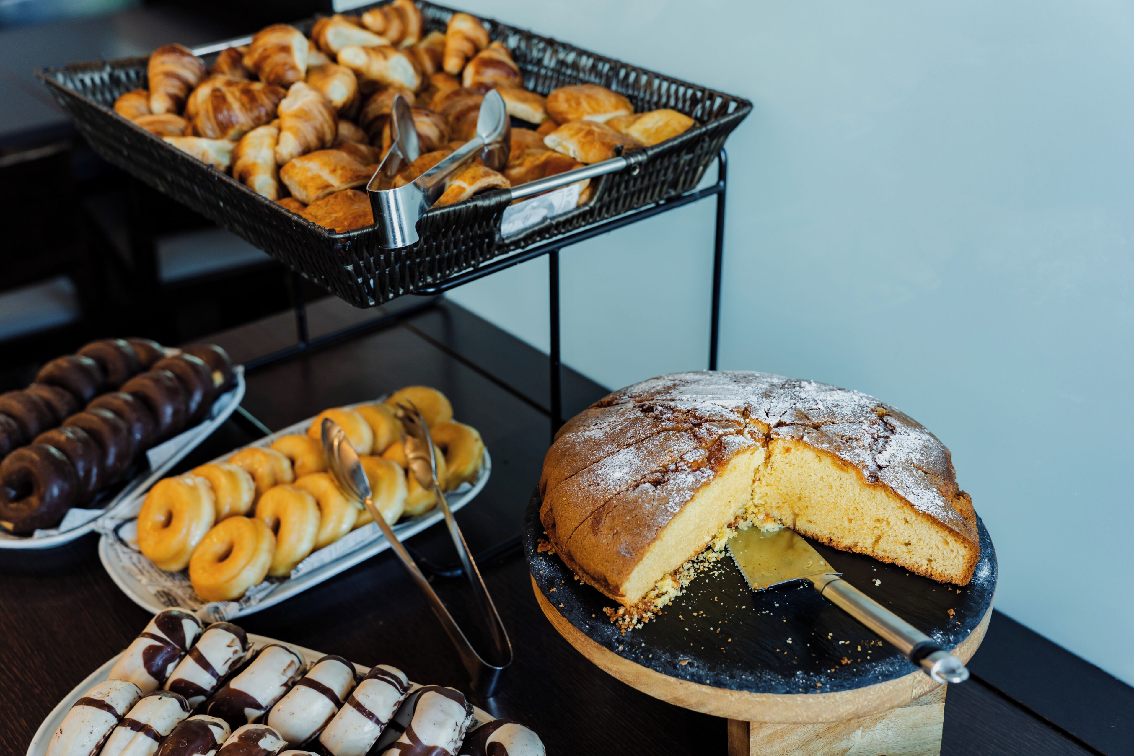 En buffet med forskellige bagværk, herunder kager og en lagkage.
