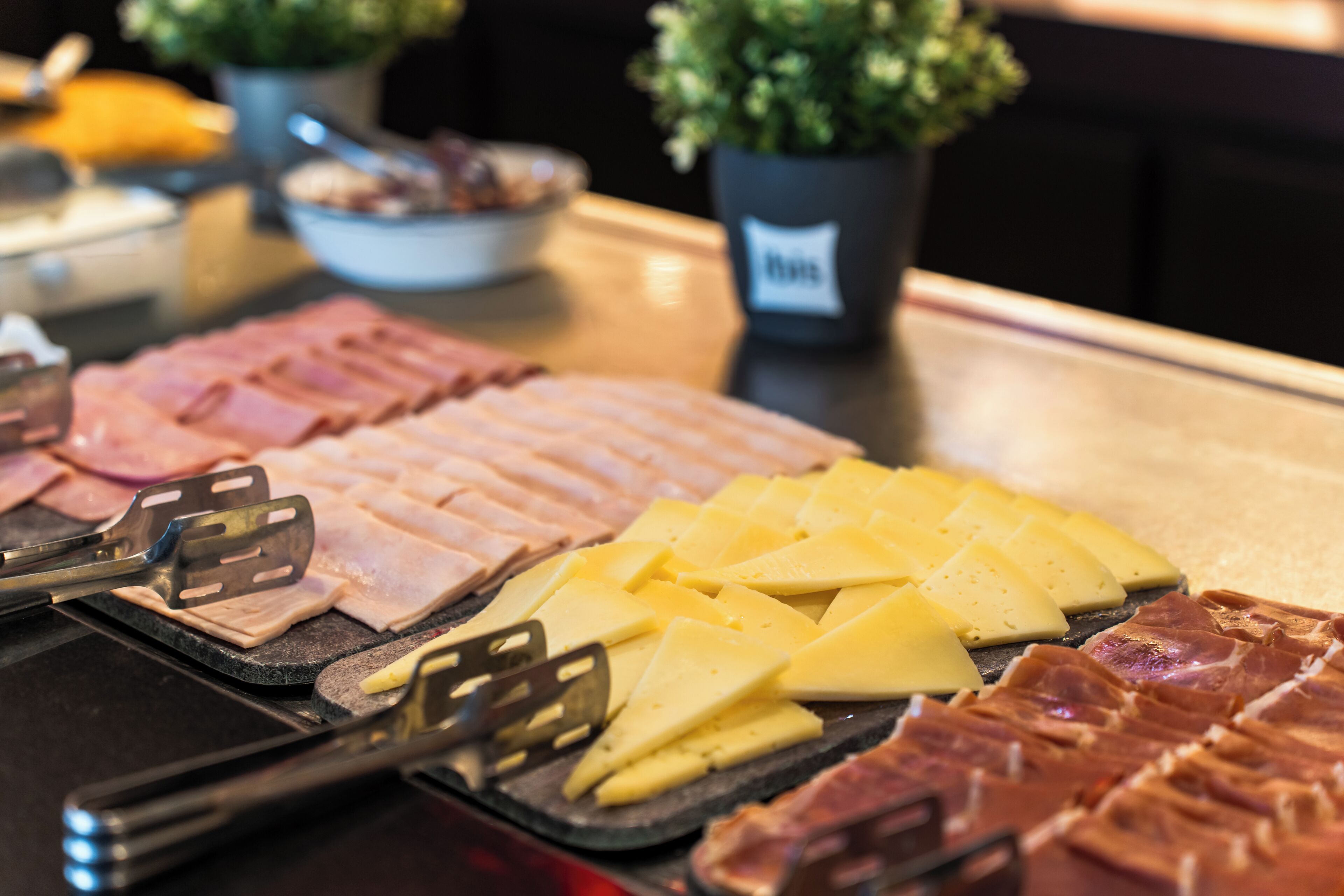 A buffet with various meats and cheeses.
