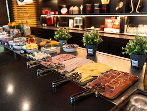 Un buffet proposant une variété de viandes, de fromages et une plante étiquetée « ibis ».