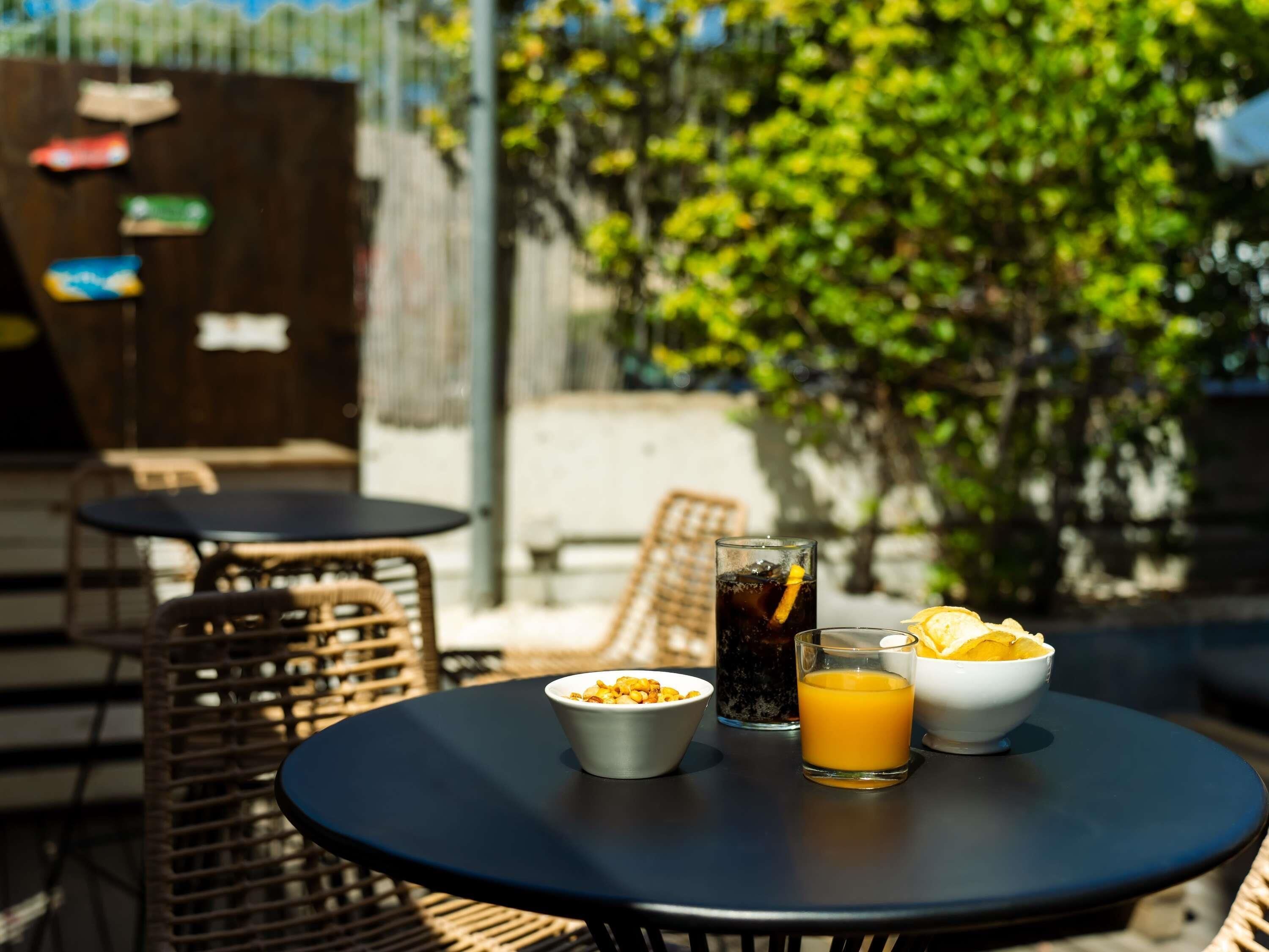 A round table with a bowl of cereal, a glass of orange juice, and a glass of soda.