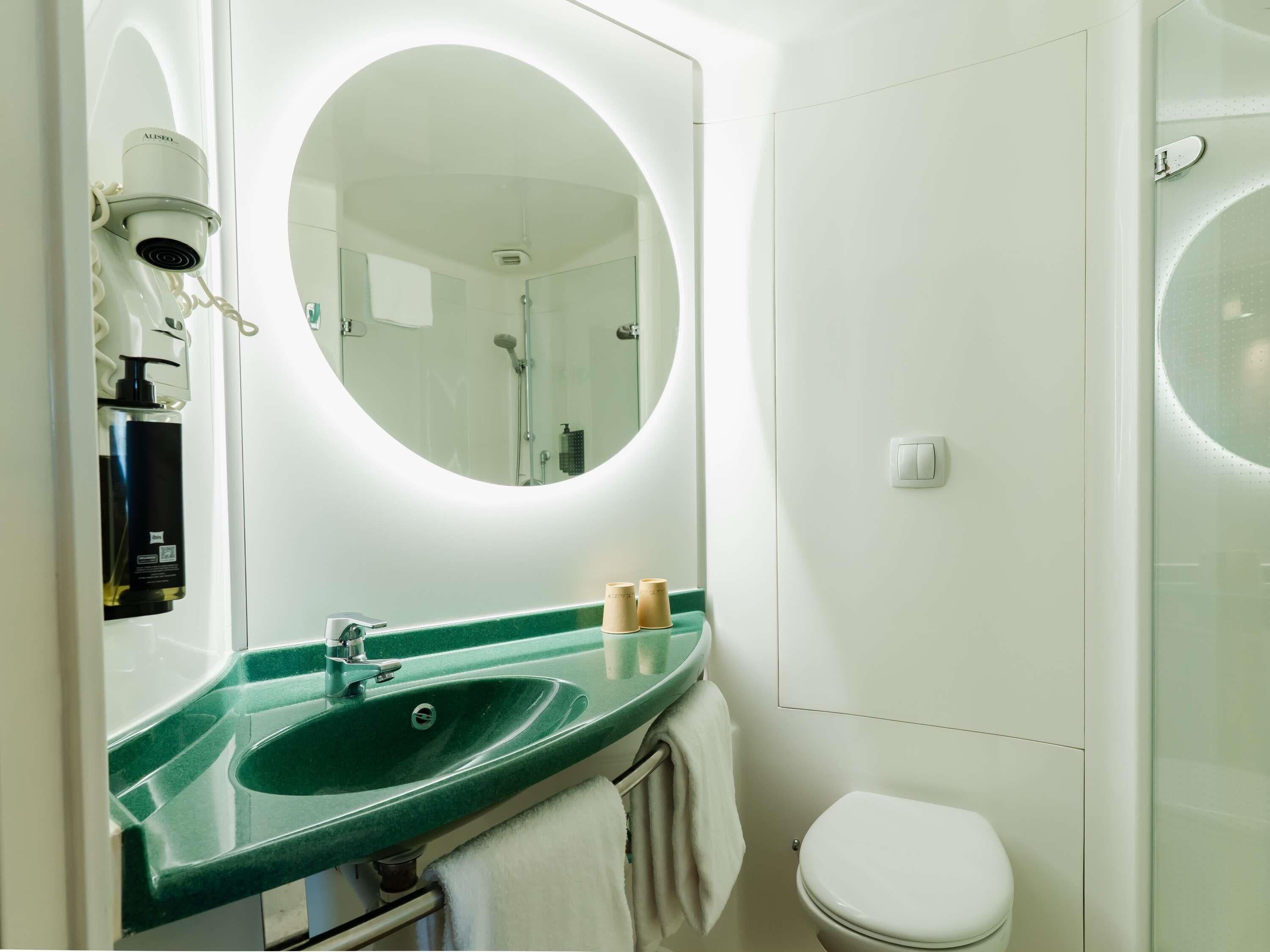 Een badkamer met een groene wastafel, een wit toilet en een grote spiegel.