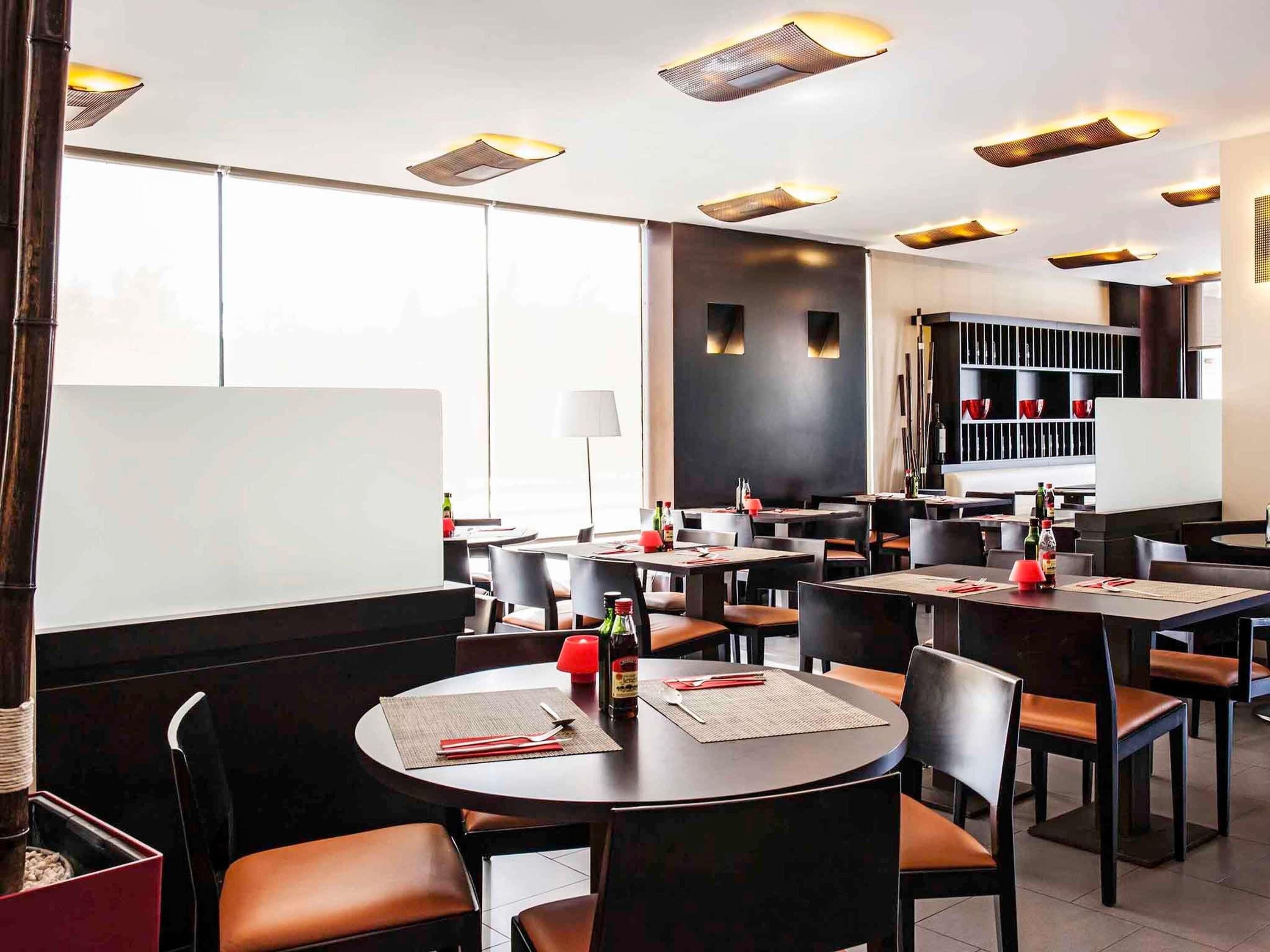 Un restaurante con mesas redondas, sillas y una zona de bar.